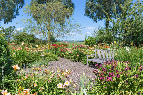 Fototapeta Naklejka Na Ścianę i Meble -  Dutch blooming garden with a retreat and wooden bench