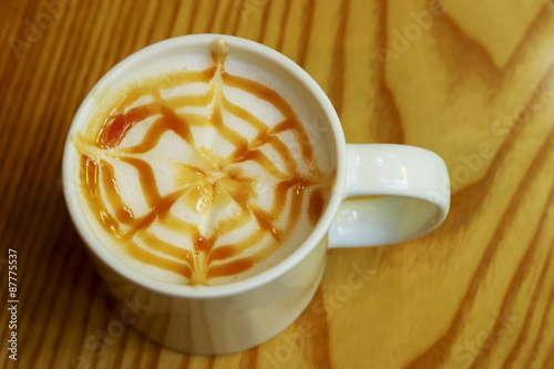 Hot caramel macchiato coffee decorated on wooden table.
