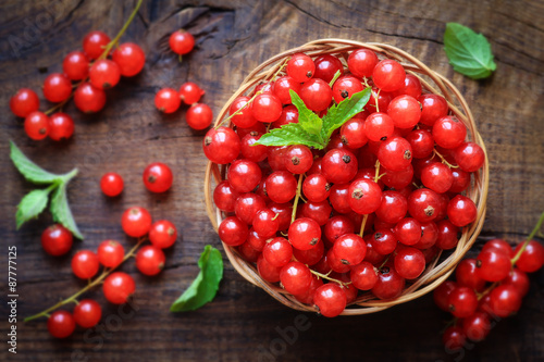 Fresh Red currants in a wiccker bowl on dark rustic wooden background