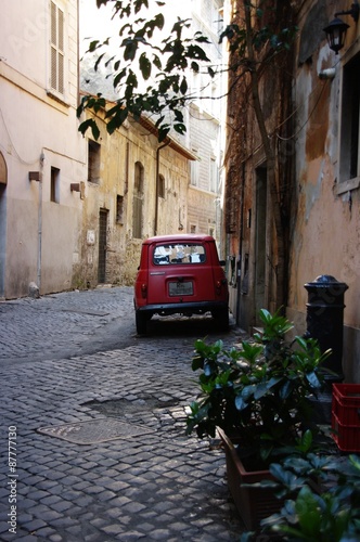 The narrow romantic Roman street and the old red car