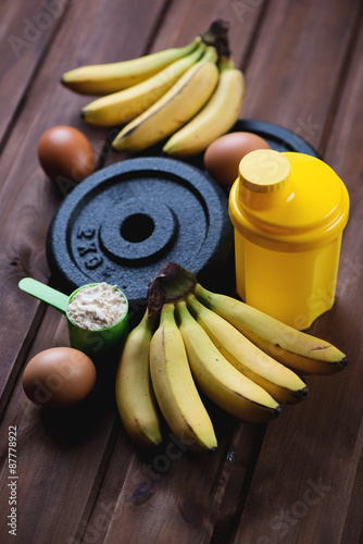 Plastic shaker, measuring scoop with protein, eggs and bananas