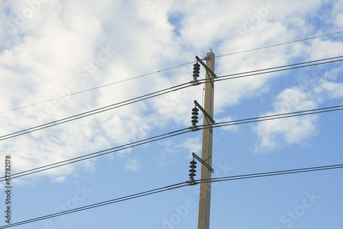 Electrical poles of high voltage 115 kV in white and blue sky.