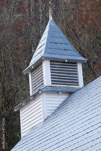 White wooden church steeple with woods backhground photo