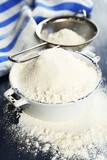 Sifting flour through sieve on wooden table, closeup