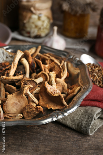 Dried mushrooms in metal tray with spices on wooden table, closeup
