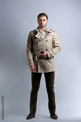 Young man in coat on gray background