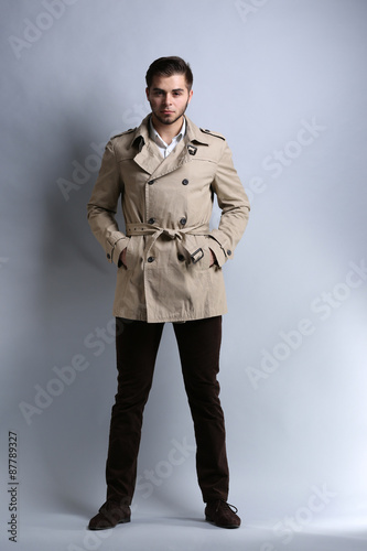 Young man in coat on gray b...