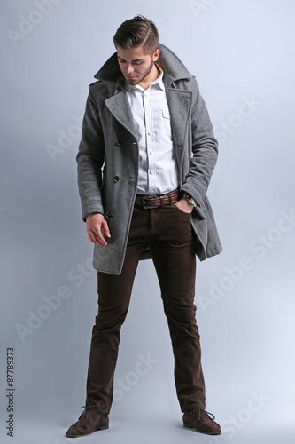 Young man in coat on gray b...