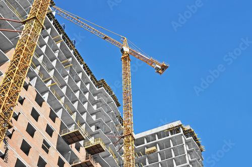  Crane and building construction site against blue sky