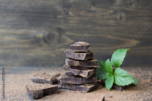 Dark chocolate with mint sprinkled with cocoa powder on a wooden surface