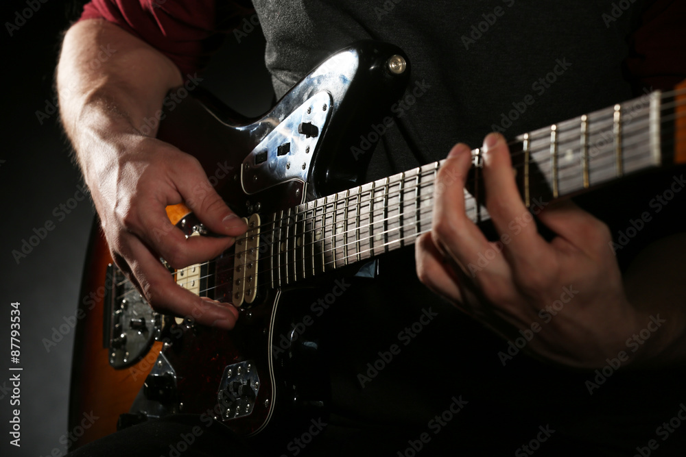 Fototapeta premium Young man playing on electric guitar close up