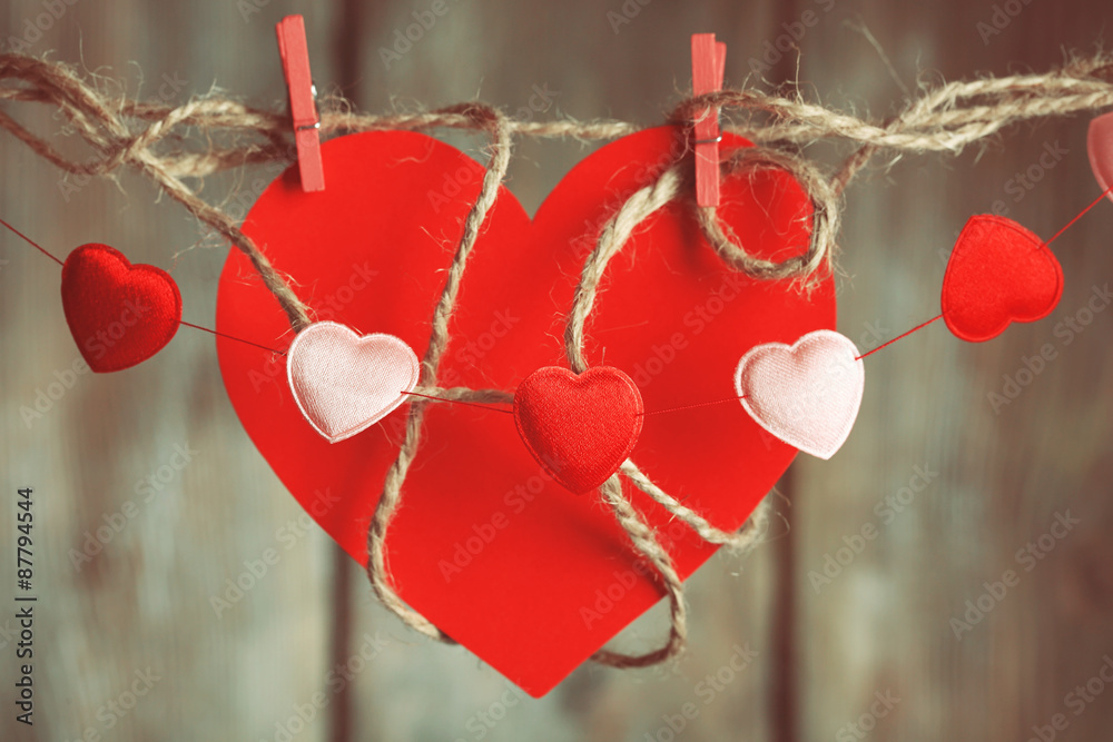 Bright hearts hanging on rope on wooden background