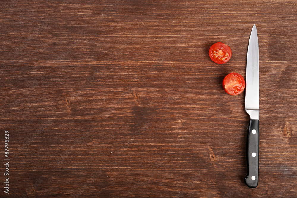 Halves of tomato with knife on wooden background Halves of tomato with knife on wooden background