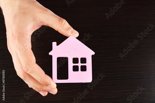 Female hand holding house on wooden background