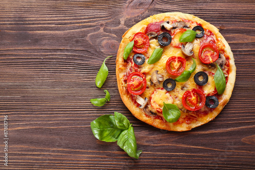 Tasty pizza with vegetables and basil on wooden background #87801796