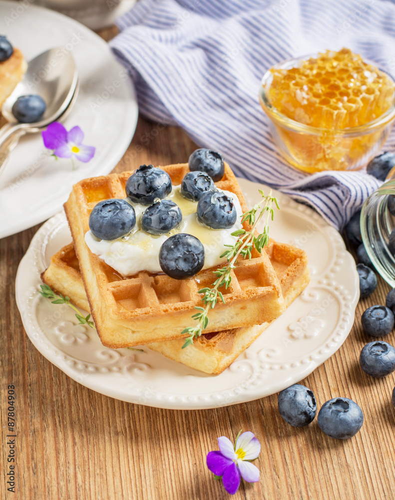 Homemade fresh crispy waffles for breakfast with blueberries and honey Homemade fresh crispy waffles for breakfast with blueberries and honey