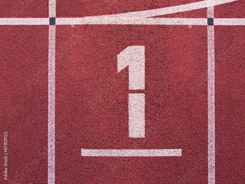 Number one. White track number on red rubber racetrack, texture of running racetracks in small outdoor stadium