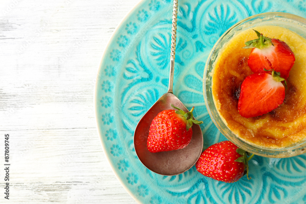 Creme brulee dessert with fresh strawberry berries on napkin, on color wooden background Creme brulee dessert with fresh strawberry berries on napkin, on color wooden background