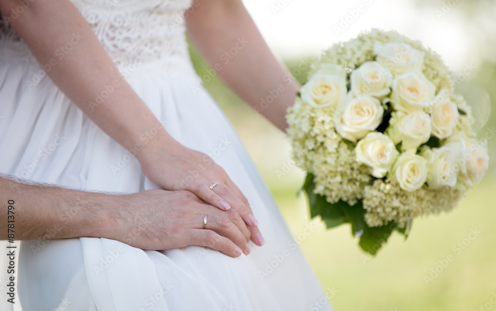 Young married couple holding hands and flower bouquet Young married couple holding hands and flower bouquet