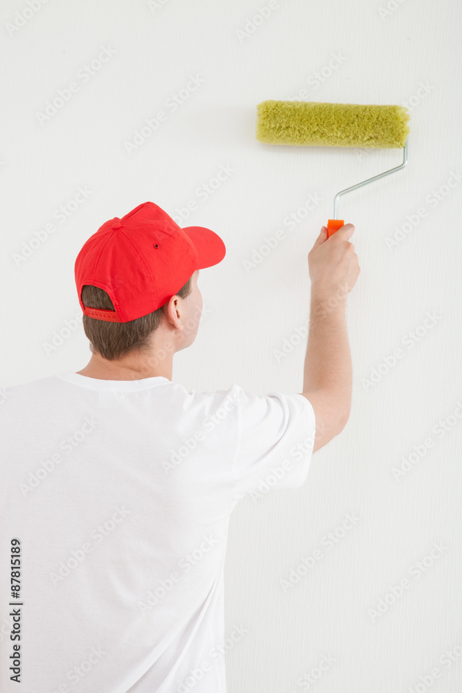 Young man painting a white wall
