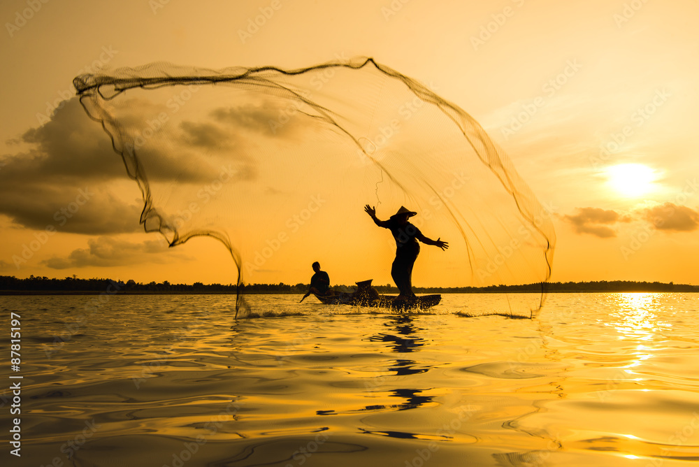 Silhouette of a fisherman throwing his net with sunset.