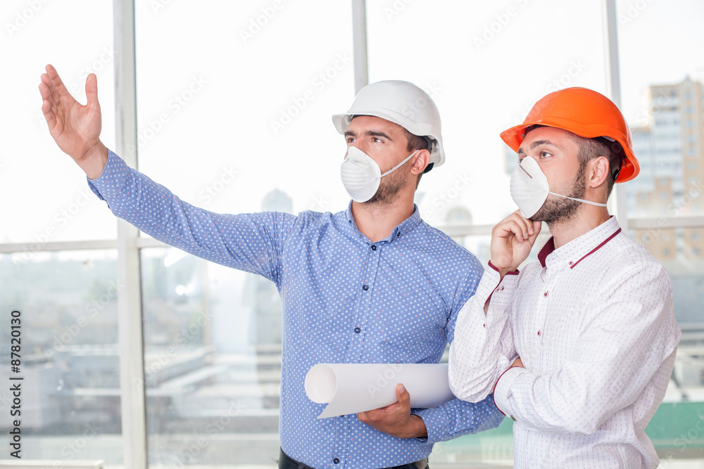 Cheerful young builders are discussing the plan of building