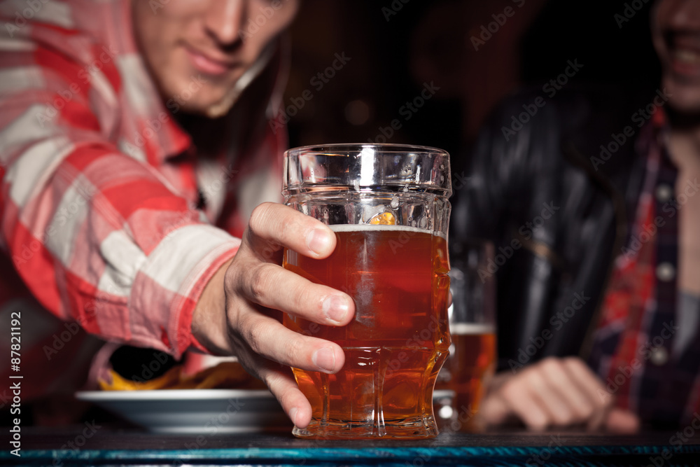 Glass of light beer on a dark pub.