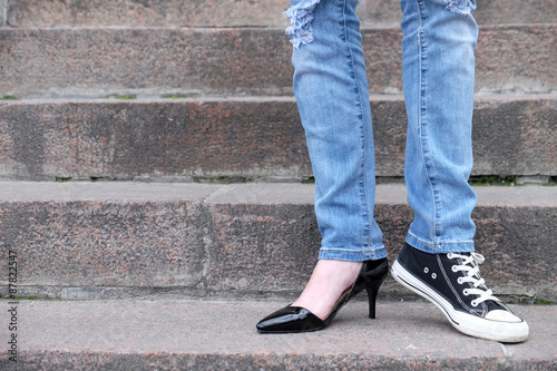 Female feet in different shoes on  stone stairs