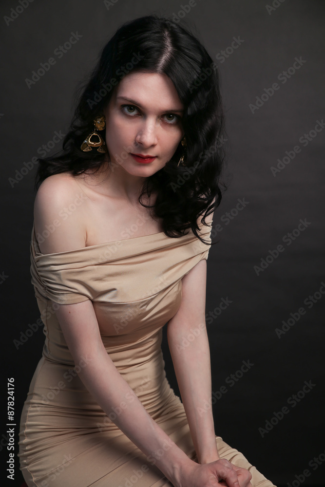 Portrait of beautiful young woman sitting over black background