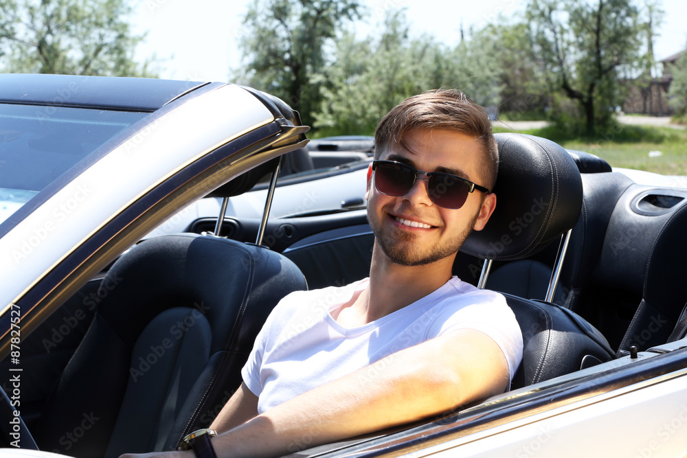 Young man in cabriolet, outdoors