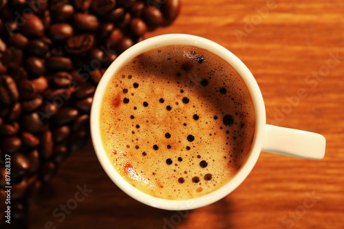 Cup of fresh coffee with beans on table, closeup © Africa Studio