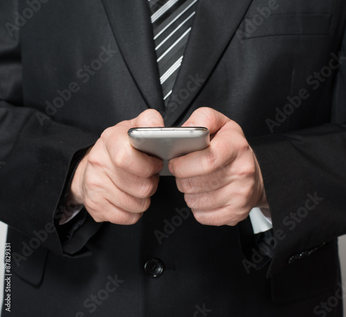 Young businessman sending message with mobile phone