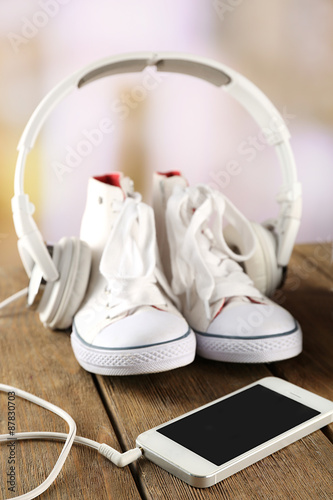 Sneakers and earphones on wooden table, closeup