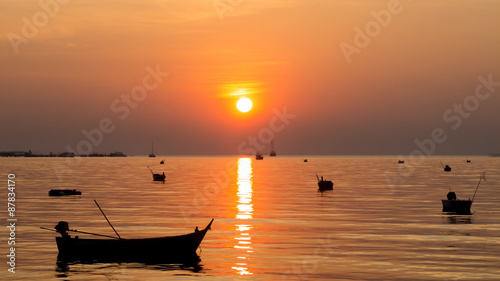 Silhouette of Small Ships in The Sea at Twilight Time with Beautiful Sun and Reflection