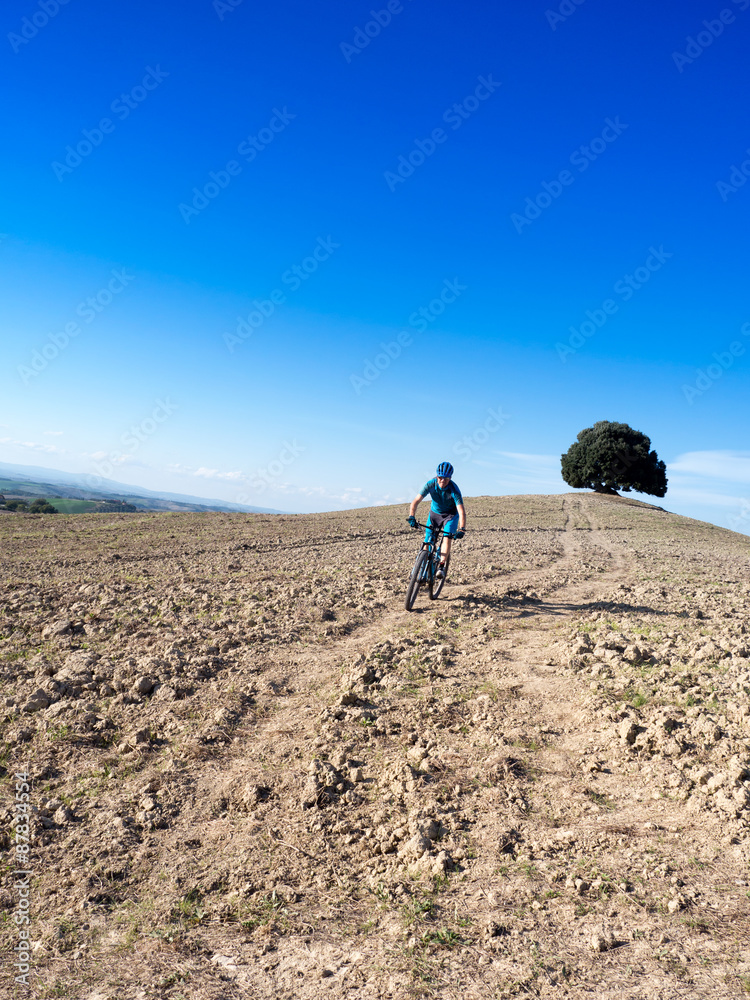Mountain biker riding through Tuscan landscape