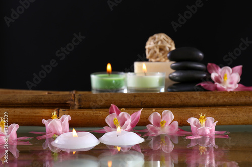 Spa still life with flowers and candlelight on black background