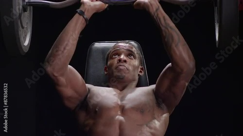 Muscular black man shoulder pressing photo