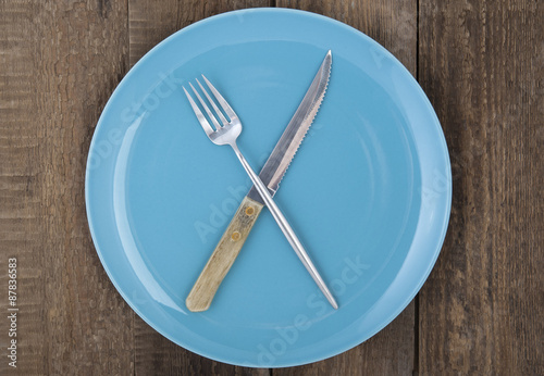 Empty plate with fork and knife on wood background..