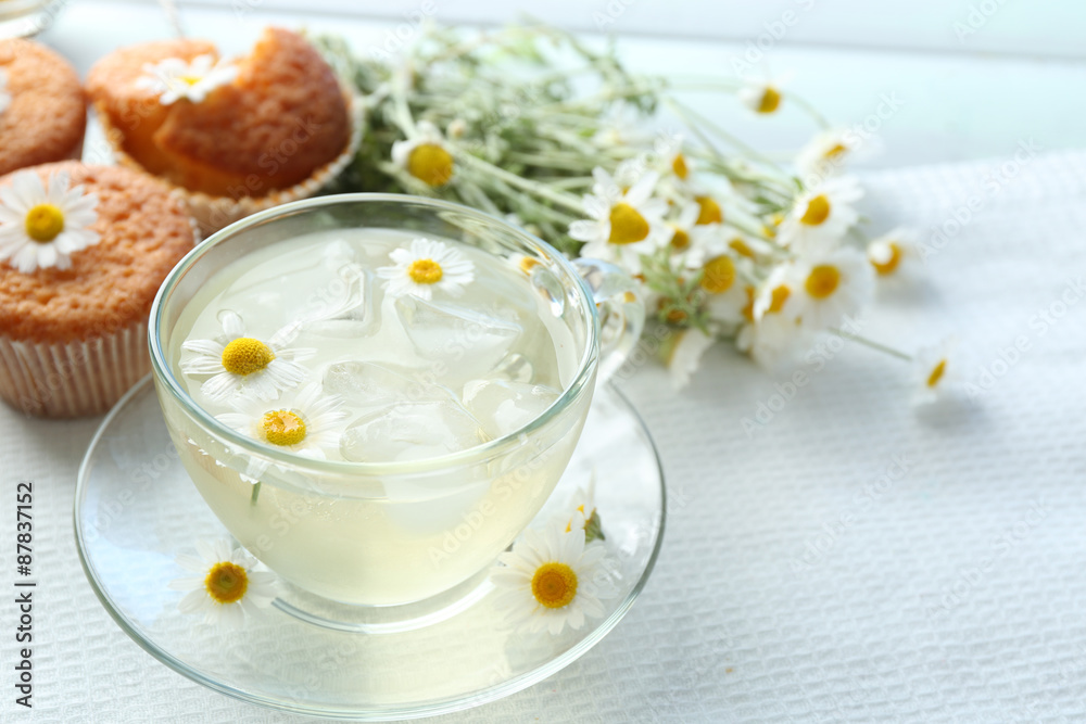 Cup of chamomile tea with chamomile flowers and tasty muffins on color wooden background Cup of chamomile tea with chamomile flowers and tasty muffins on color wooden background