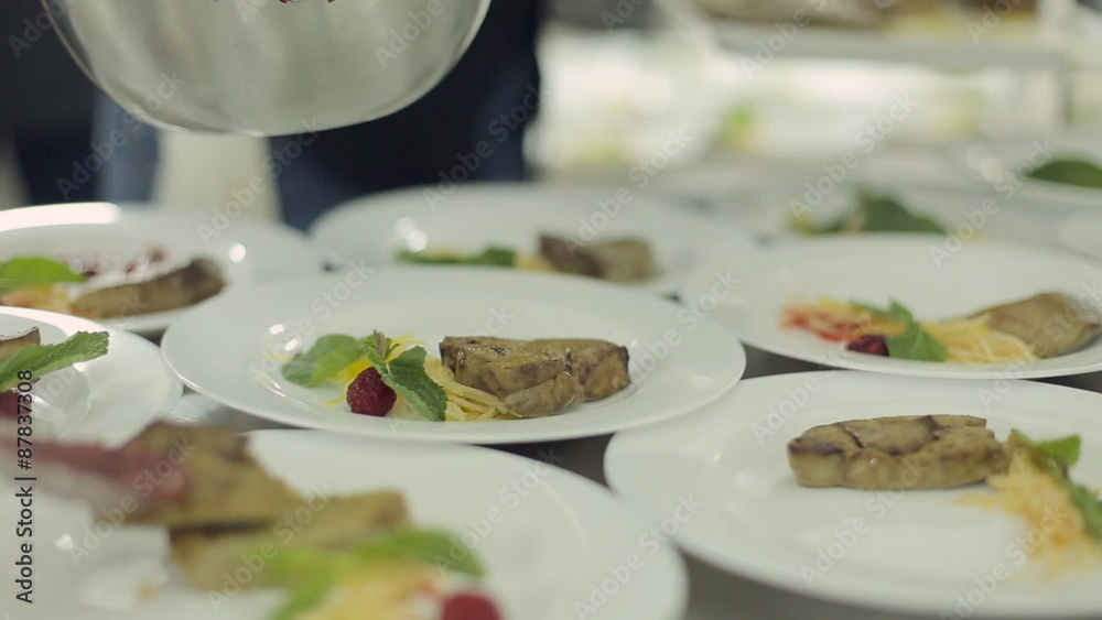 Chef spread foie gras on plates and pours with berry sauce