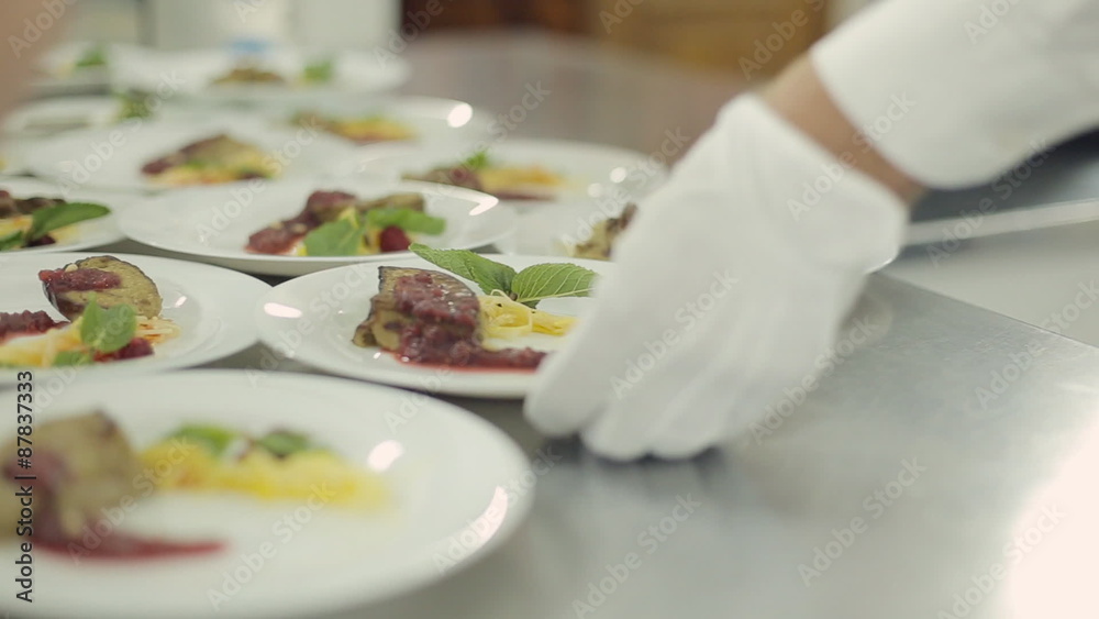 Chef spread foie gras on plates, pouring berry sauce and waiters