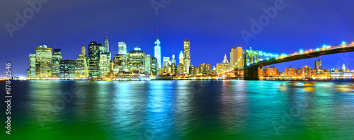 Panorama of Manhattan skyline and Brooklyn Bridge at night.