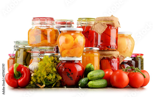 Jars with pickled vegetables and fruity compotes on white