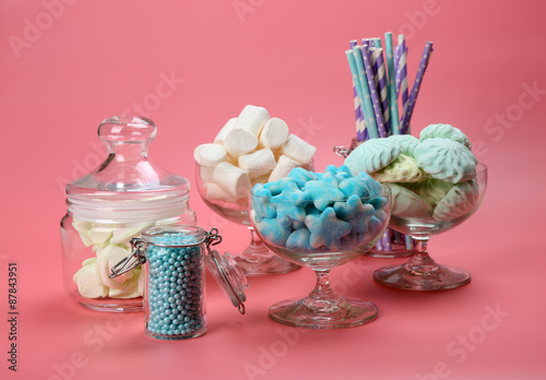 Fluffy candies in glassware on pink background