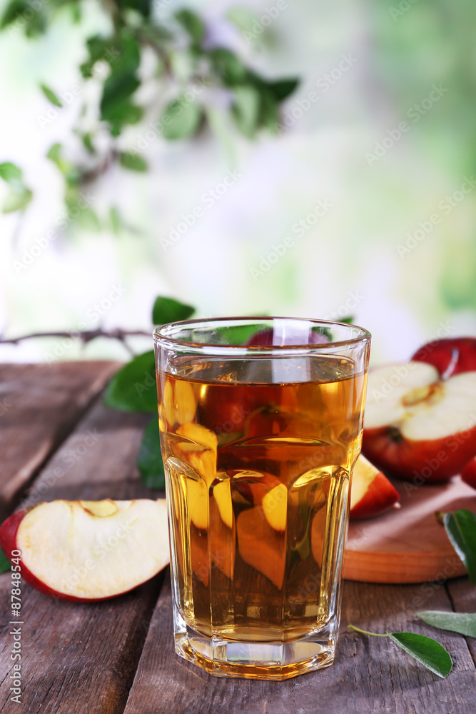 Glass of apple juice with red apples on wooden table on blurred background Glass of apple juice with red apples on wooden table on blurred background