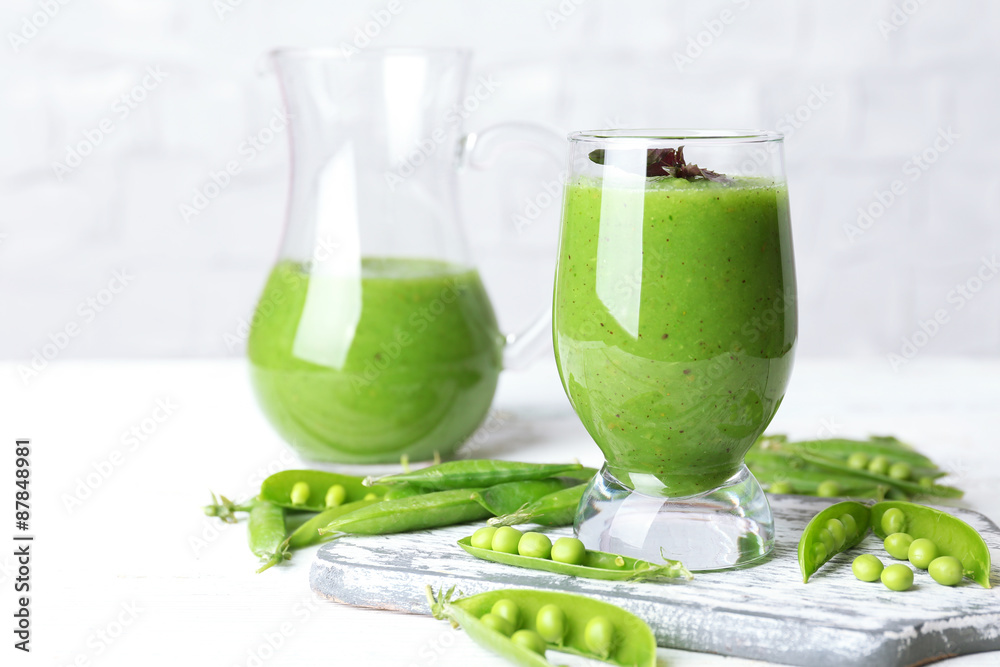 Healthy green smoothie with peas on wooden table on white wall background Healthy green smoothie with peas on wooden table on white wall background