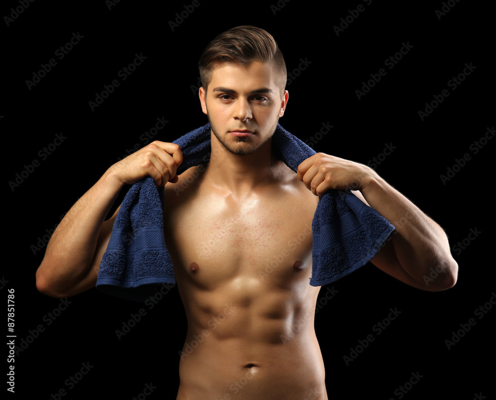 Fototapeta premium Muscle young man holding towel on dark background