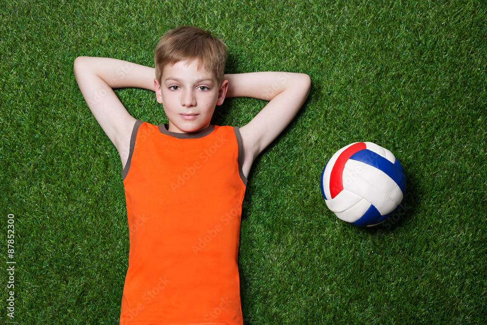 Boy lying with ball on green grass close up Boy lying with ball on green grass close up