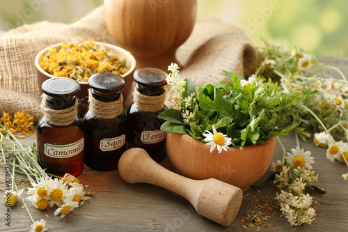 Fototapeta Naklejka Na Ścianę i Meble -  Herbs, berries and flowers with mortar, on wooden table background