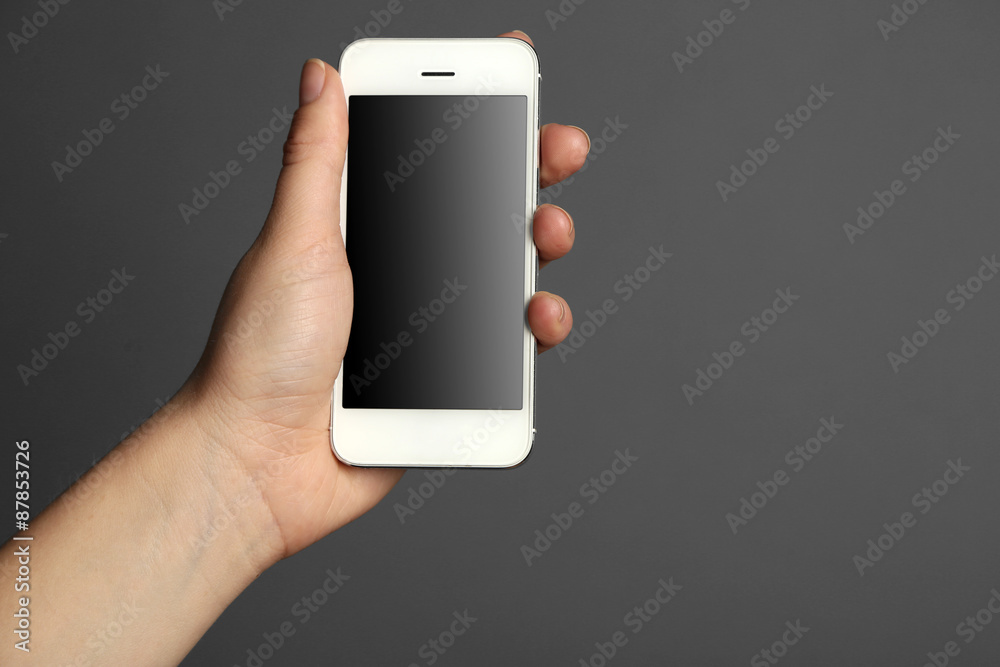 Hand holding mobile smart phone on gray background Hand holding mobile smart phone on gray background